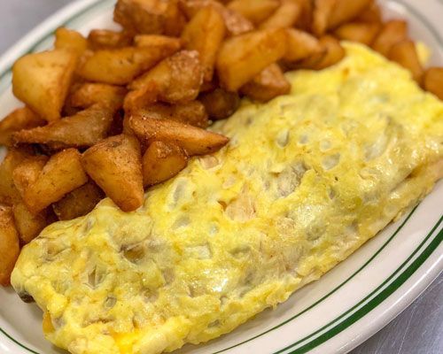 Omelet with golden potatoes on a white plate with green trim; close-up shot.