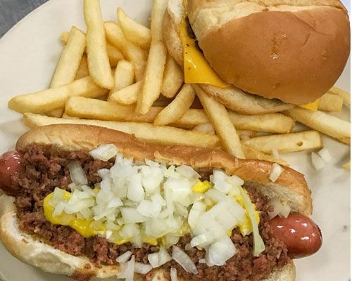 Plate with a chili dog, cheeseburger, and fries. Yellow mustard and diced onions on the dog.