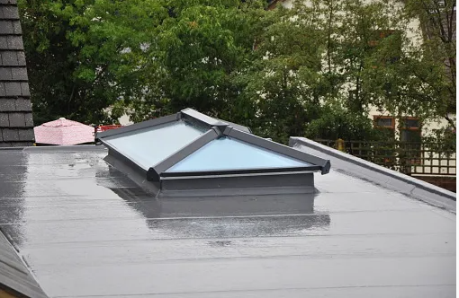 A brick house with a black roof and white windows.