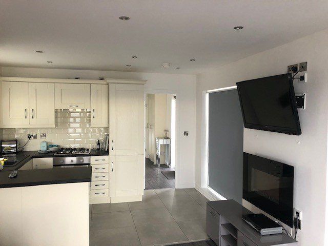 A kitchen with white cabinets and a flat screen tv