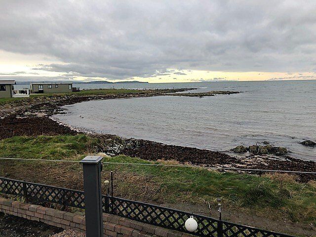 A view of the ocean from a balcony with a fence in the foreground.