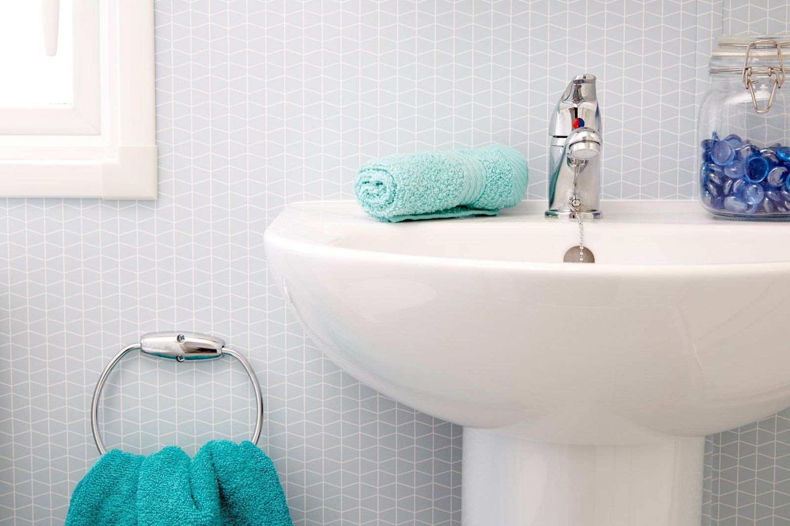 A bathroom sink with a towel and a jar of blue beads on the counter.