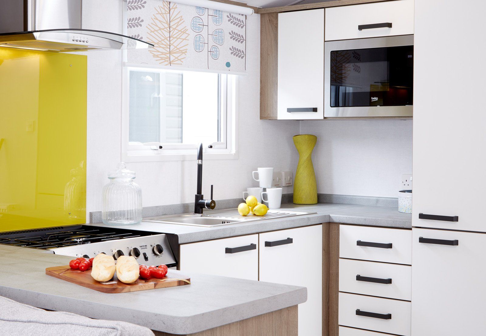 A kitchen with white cabinets , a stove , a sink , and a microwave.