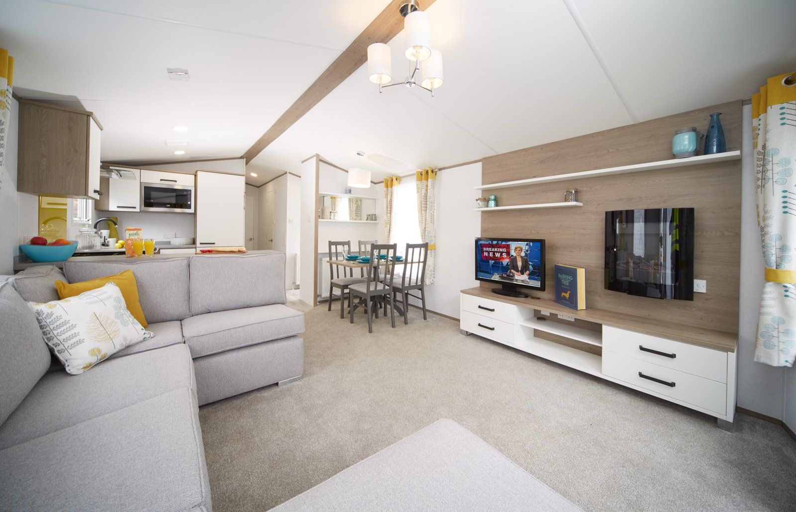 A living room with a couch , television , dining table and chairs.