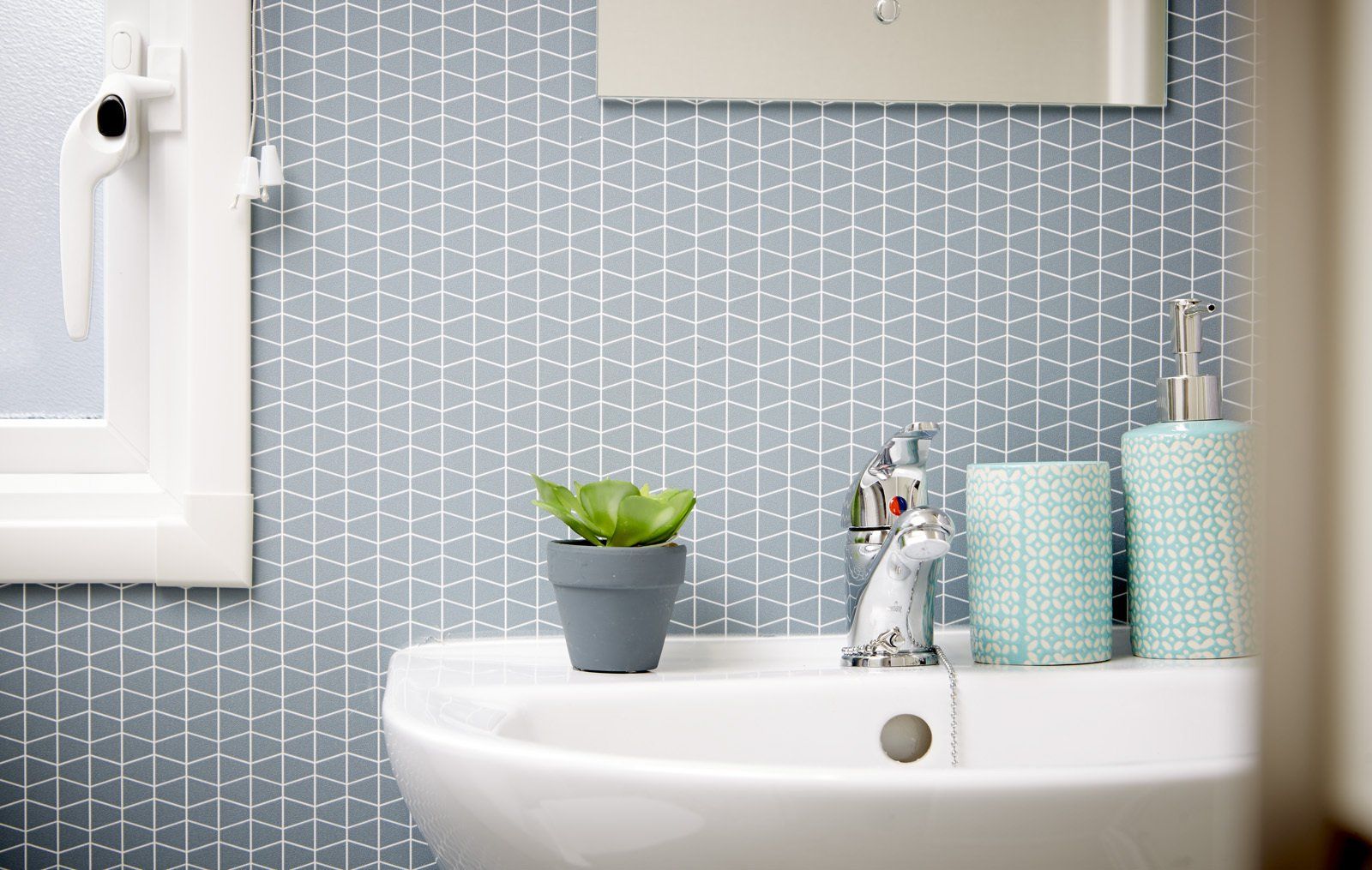 A bathroom sink with a potted plant on top of it.