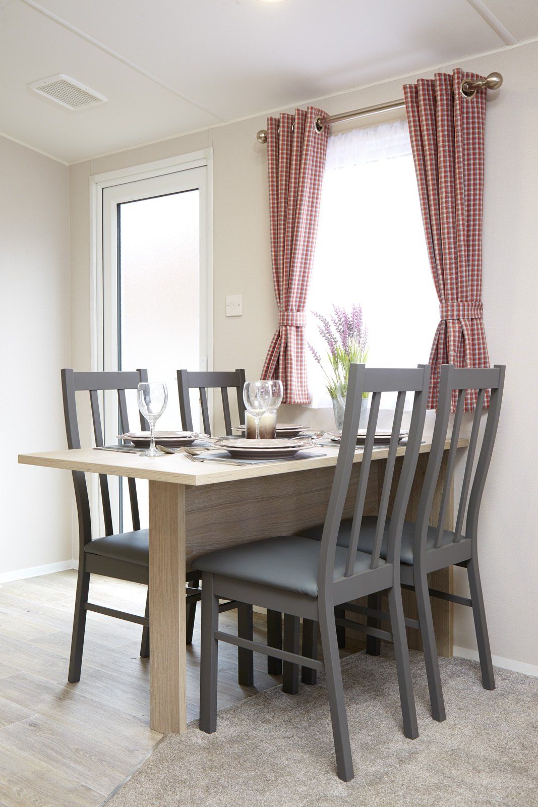 A dining room with a table and chairs in front of a window.