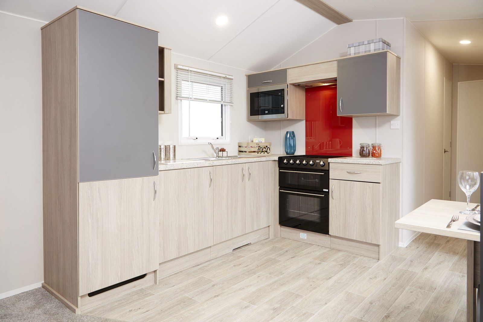 A kitchen with wooden cabinets , a stove , a microwave and a table.