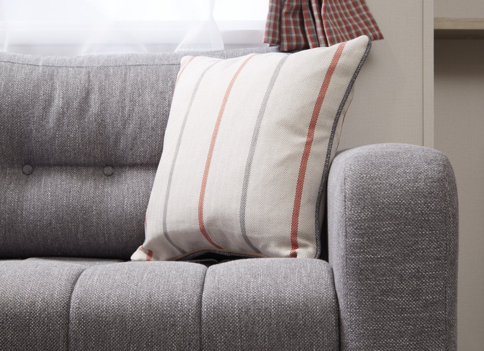 A grey couch with a striped pillow on it.