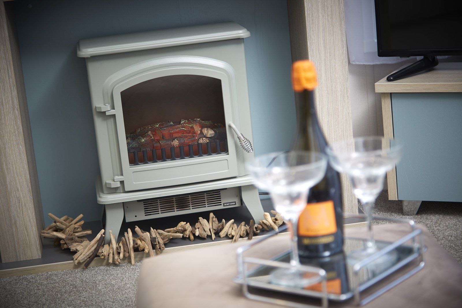 A fireplace with a bottle of champagne and two glasses on a tray.