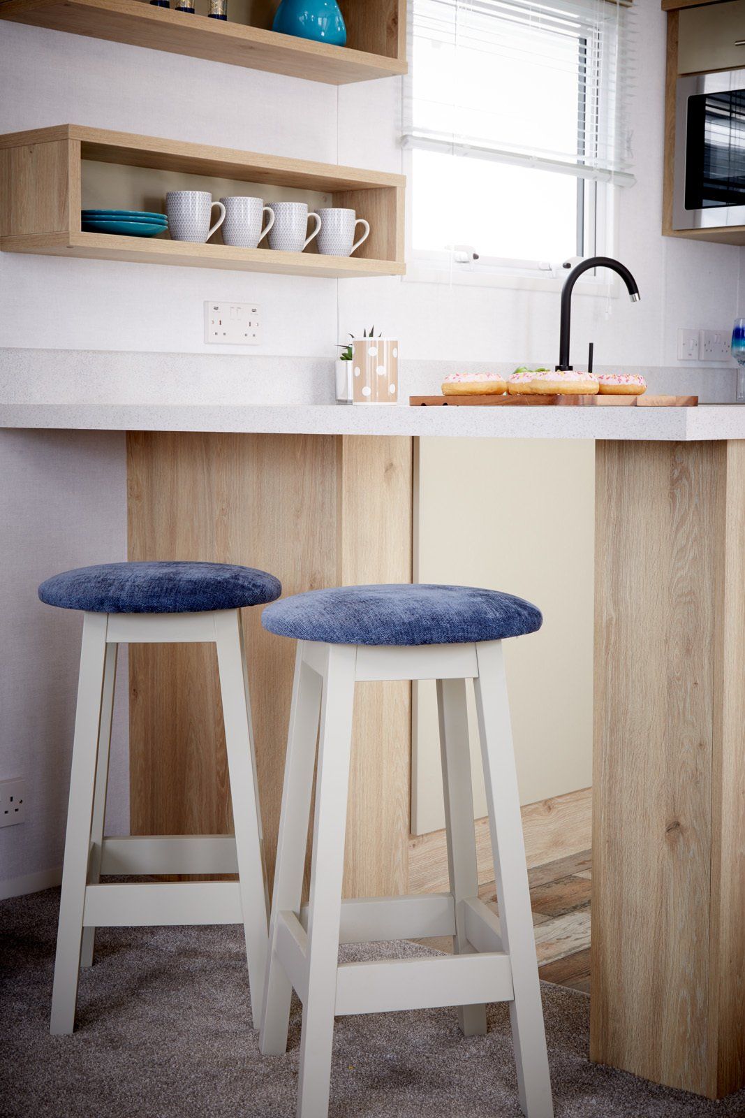 A kitchen with two bar stools and a sink.