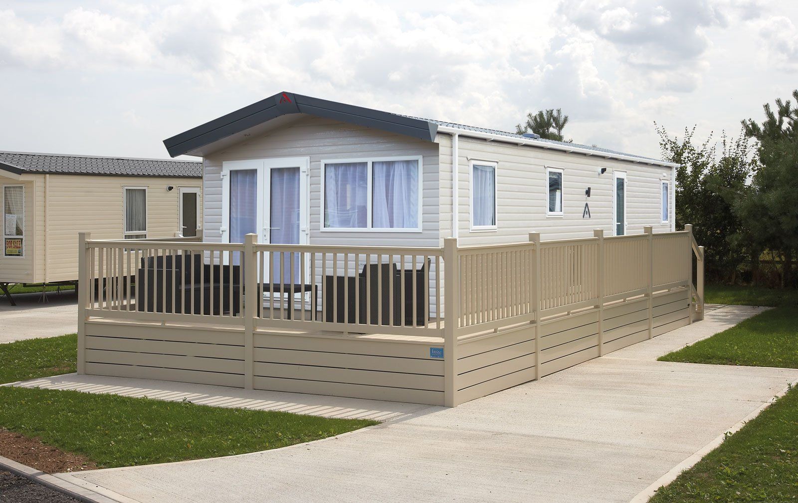 A white mobile home with a fence around it