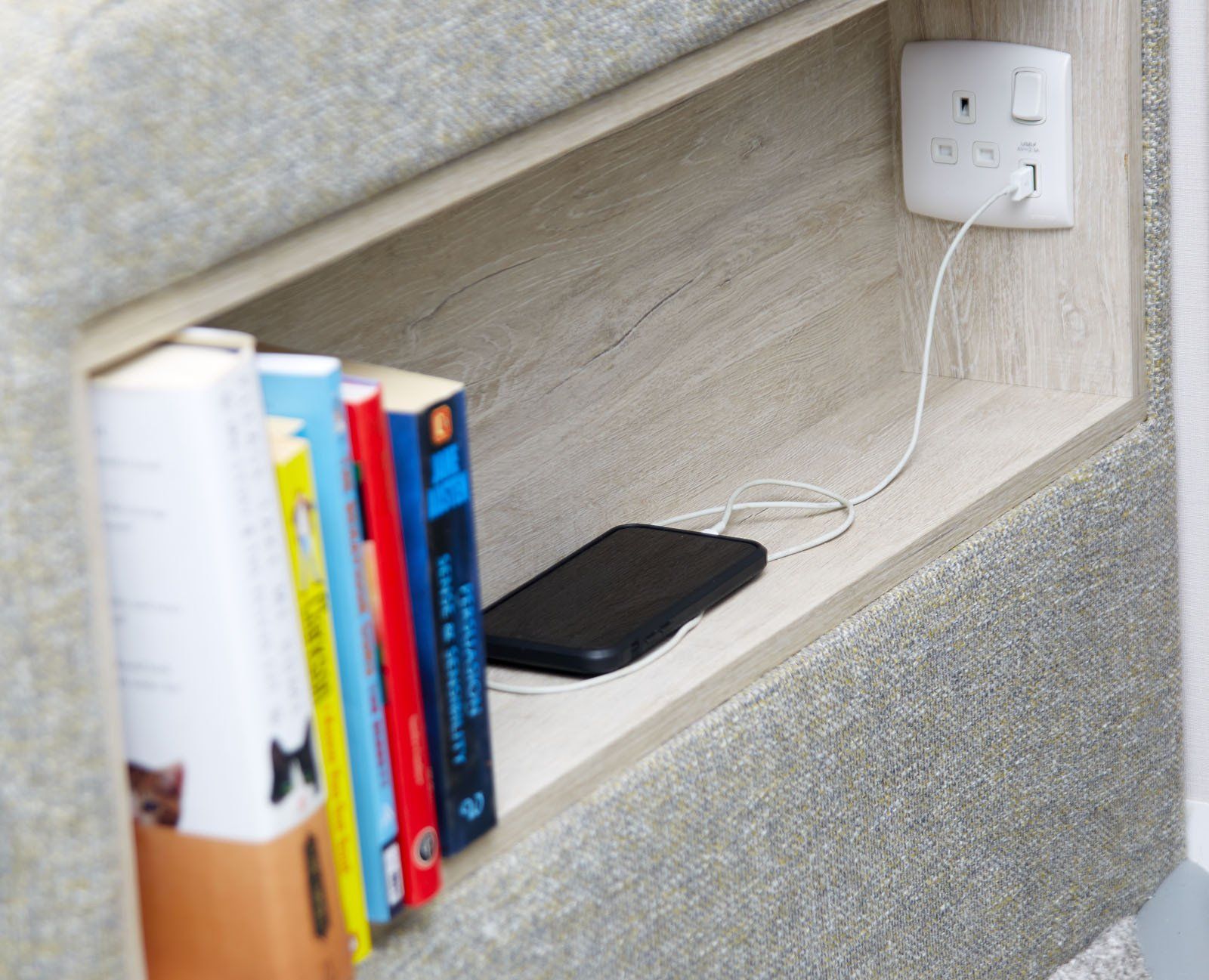 A shelf with books and a cell phone on it