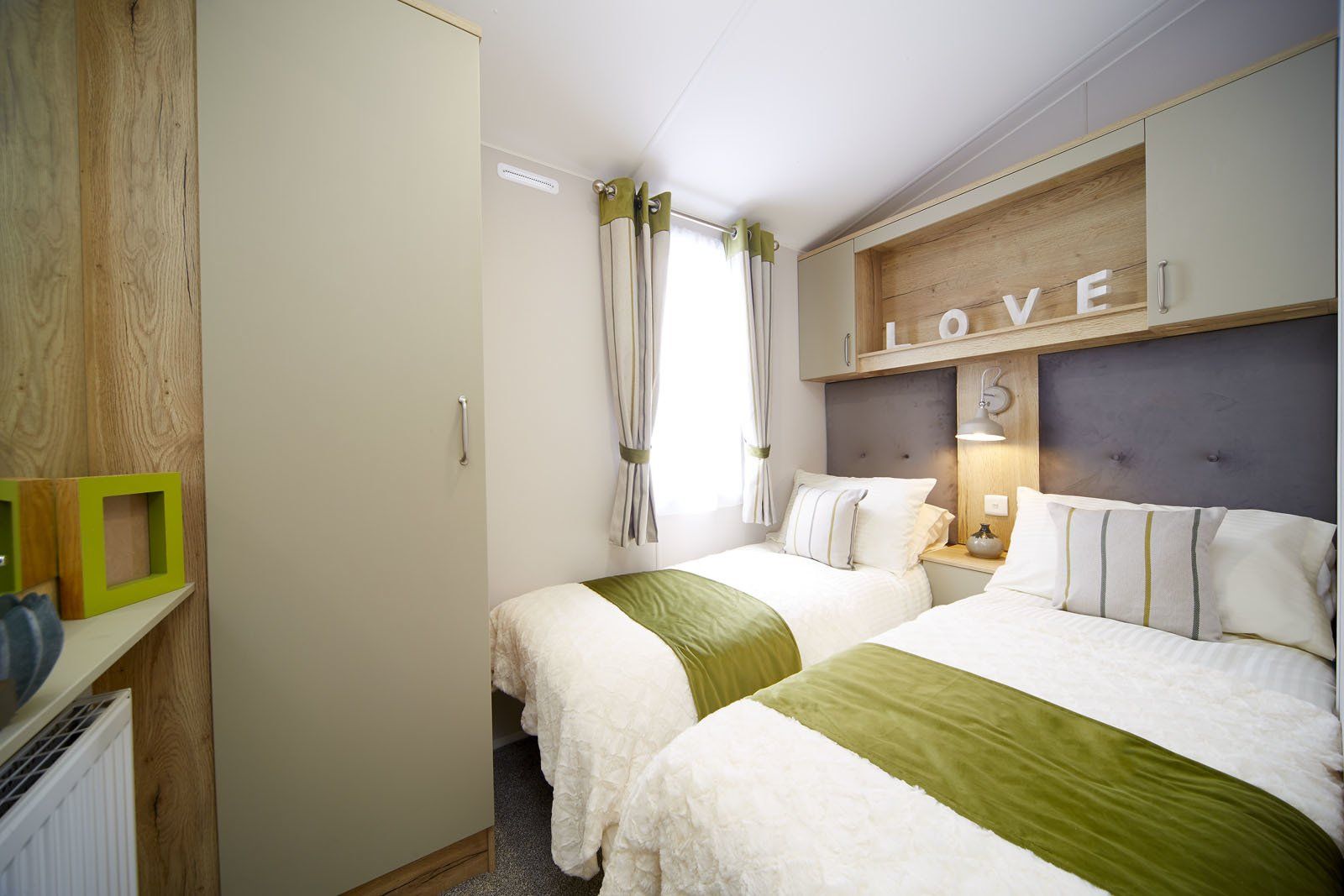 A bedroom with two beds and a sign that says `` love ''.