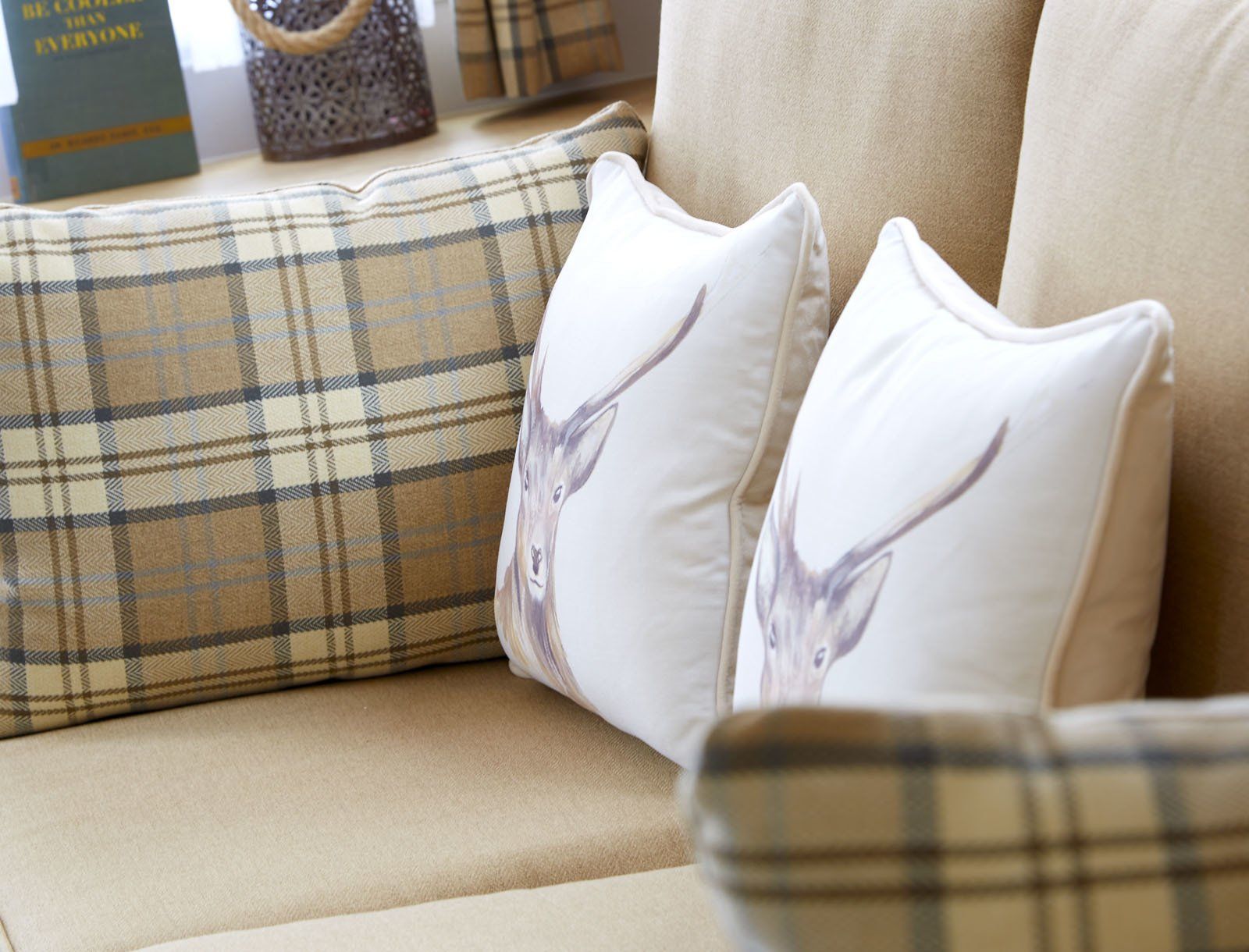 A couch with plaid pillows and a deer pillow on it