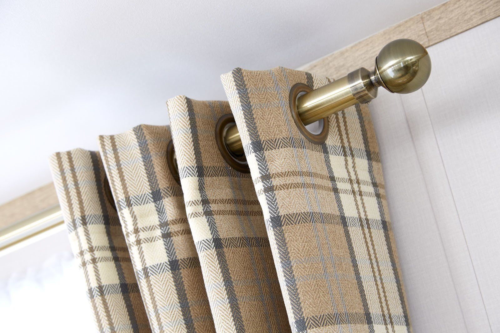 A pair of plaid curtains hanging on a brass pole