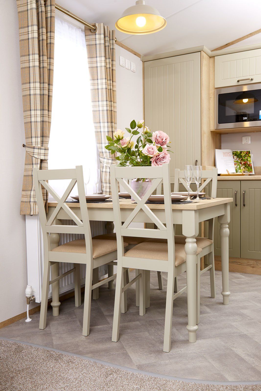 A dining room with a table and chairs and a vase of flowers on the table.