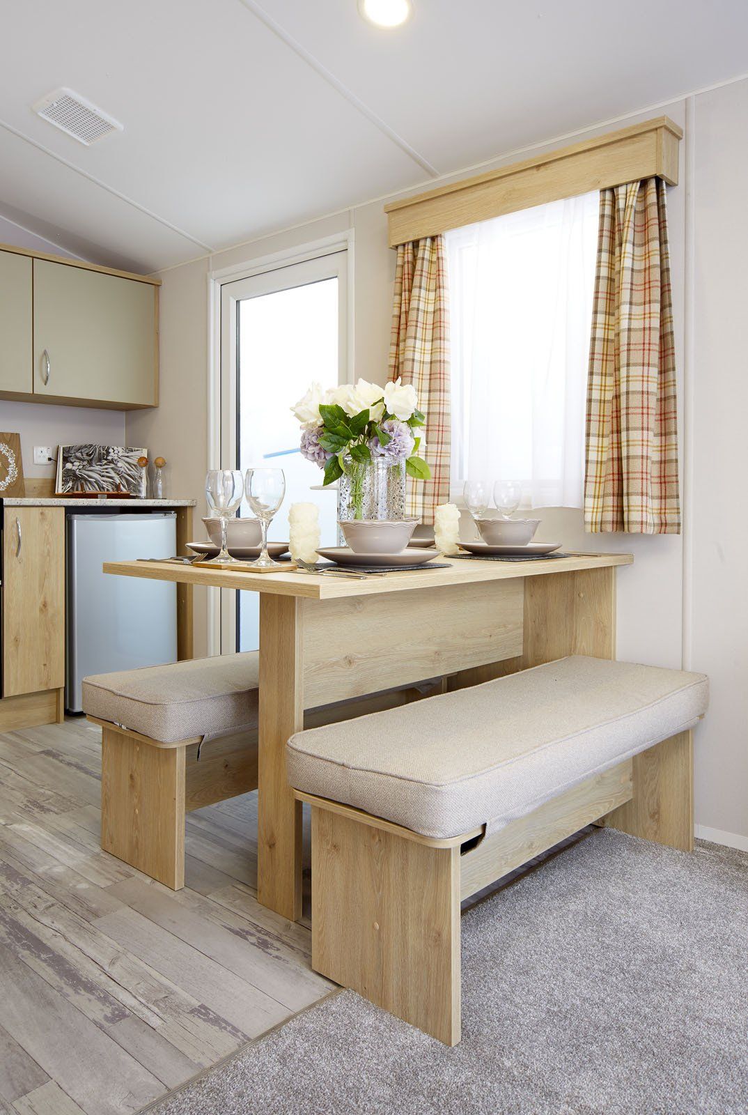 A dining room in a mobile home with a table and benches.