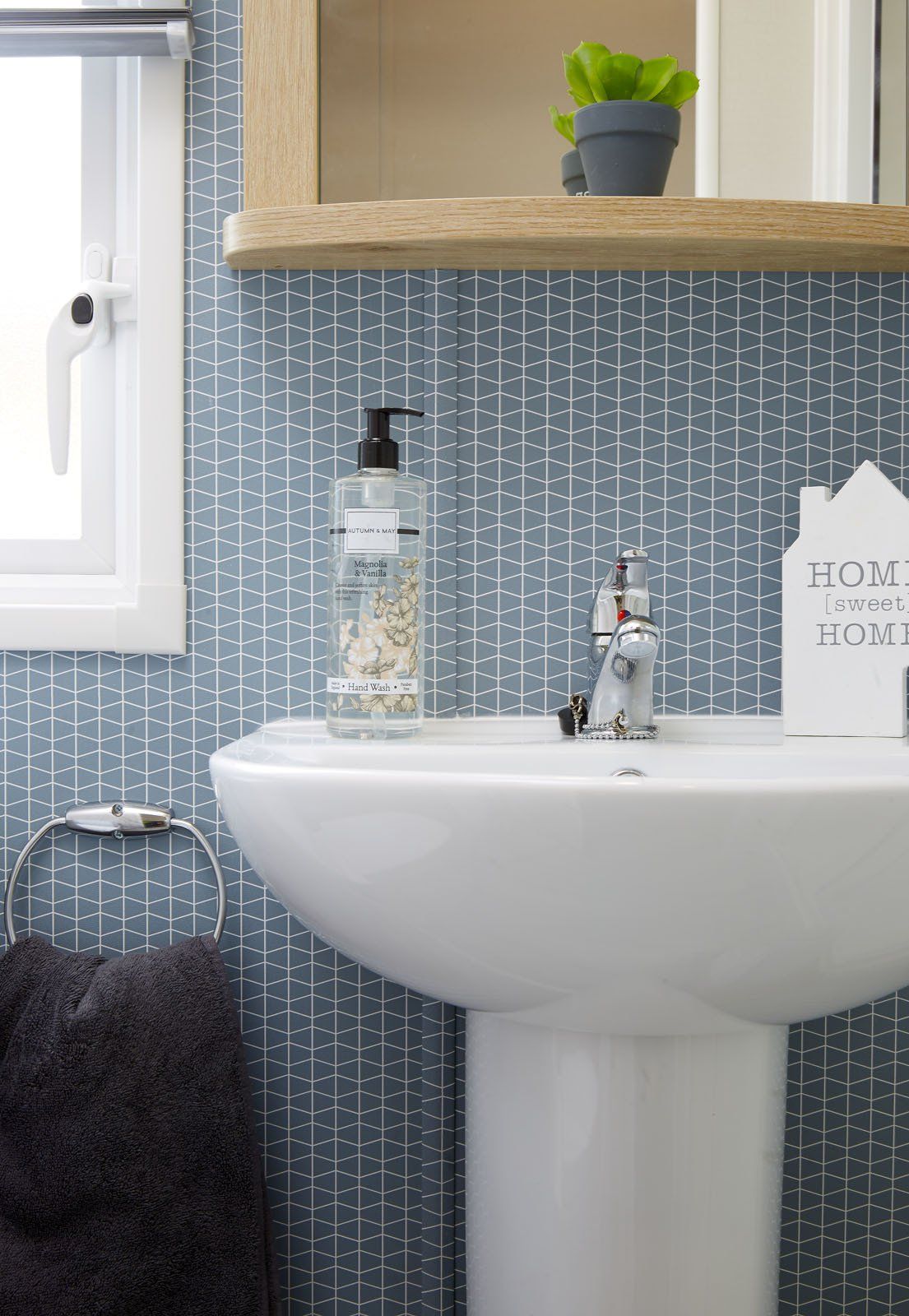 A bathroom with a sink , mirror and soap dispenser.