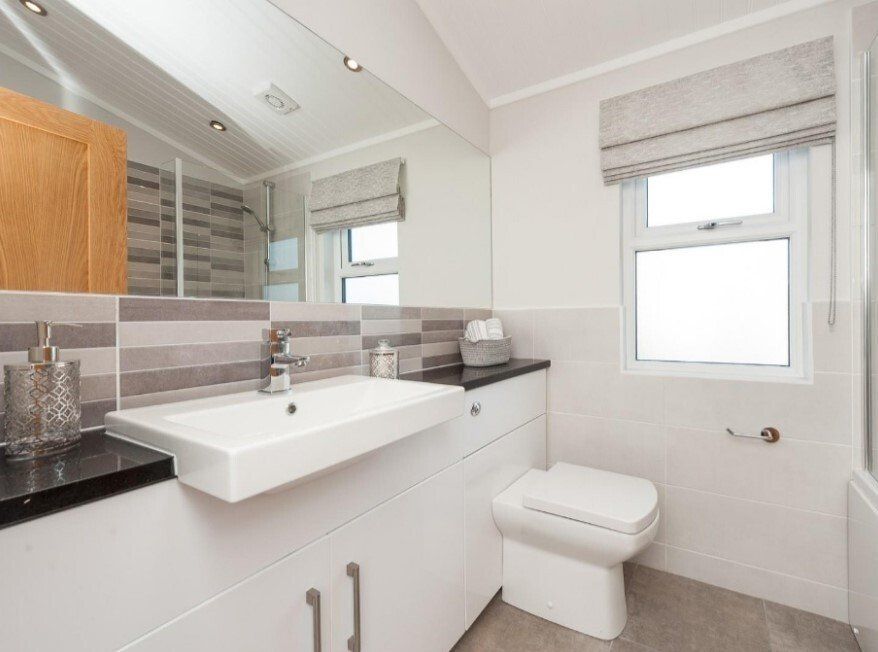 A bathroom with a sink , toilet , mirror and window.