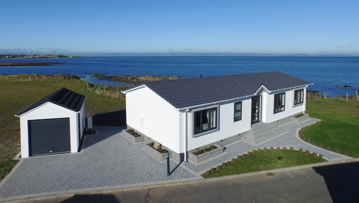 An aerial view of a house with a garage and a view of the ocean.