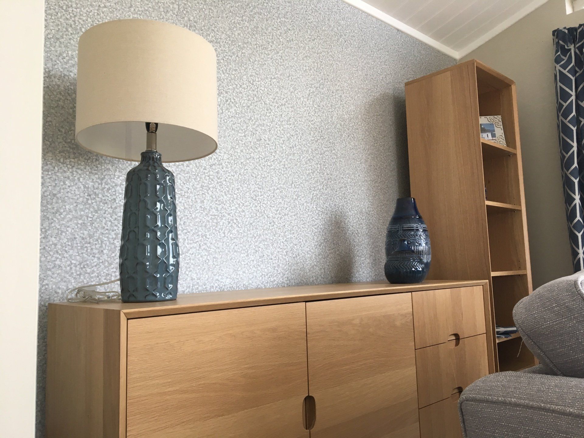 A lamp is sitting on a wooden dresser in a living room.