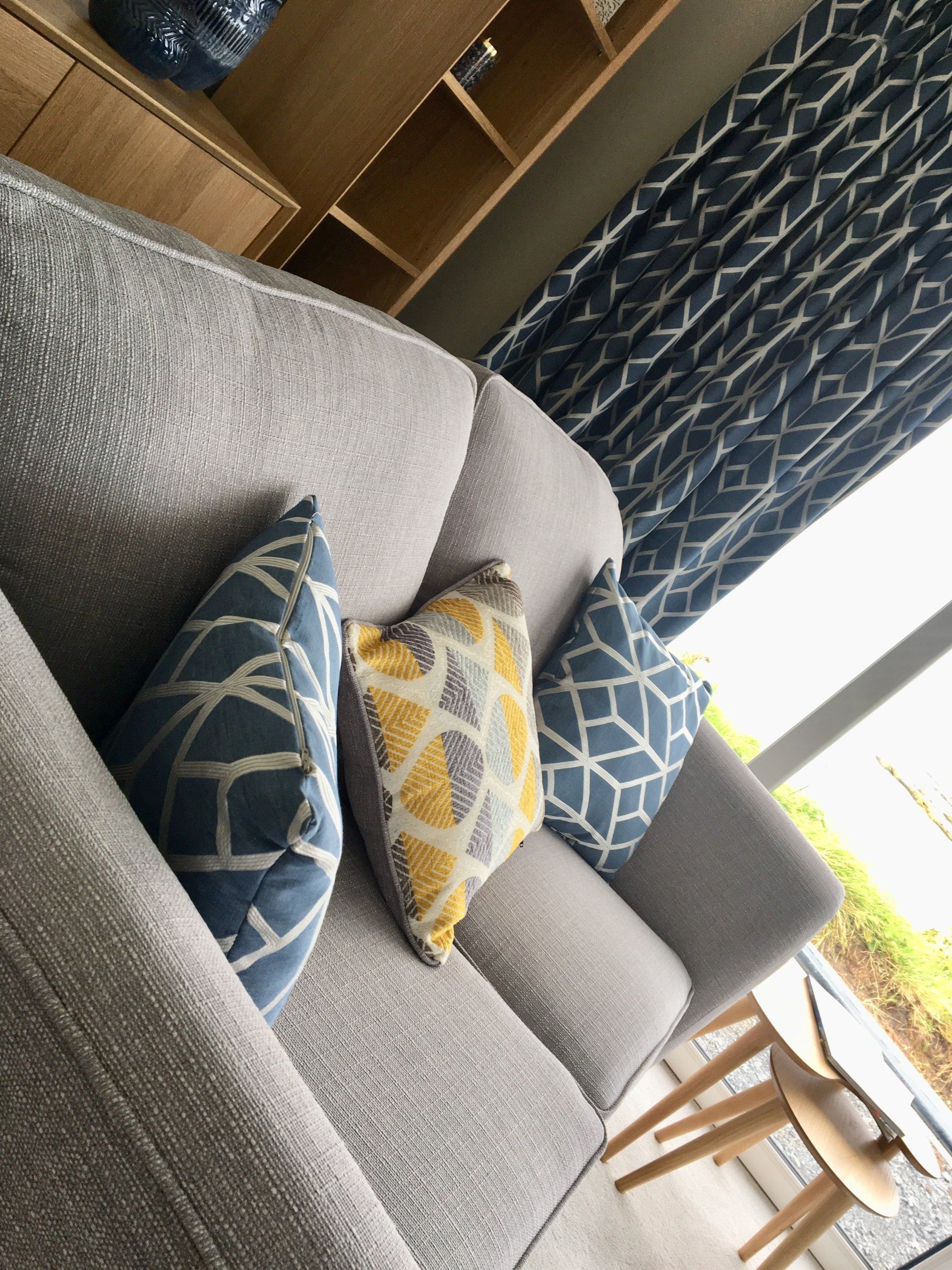 A living room with a grey couch and blue and yellow pillows