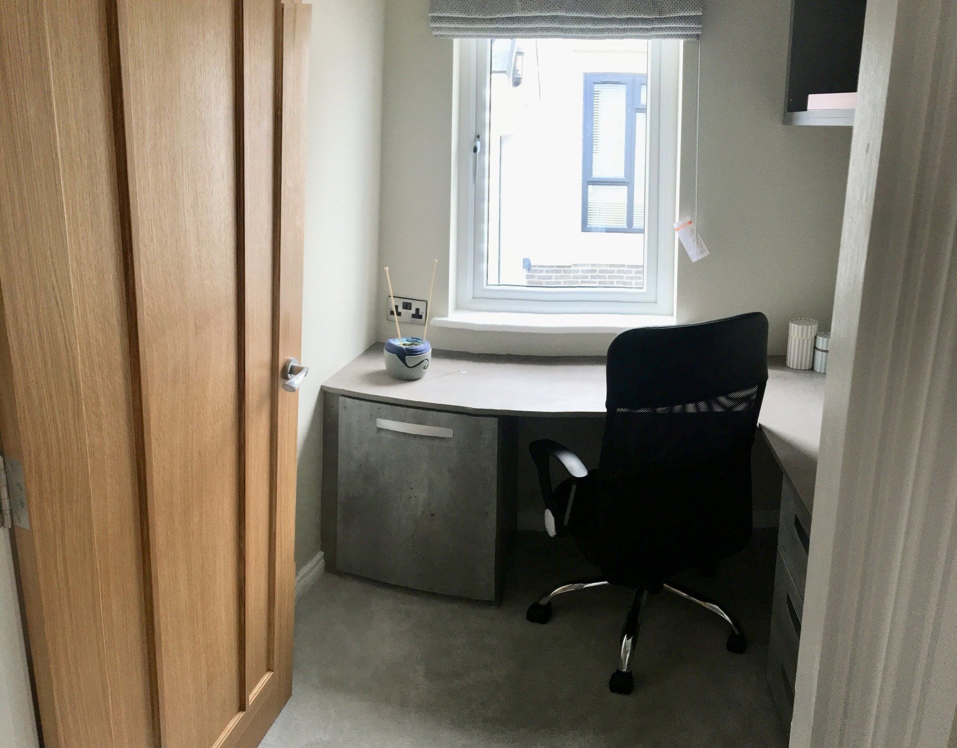 A small room with a desk and chair in front of a window