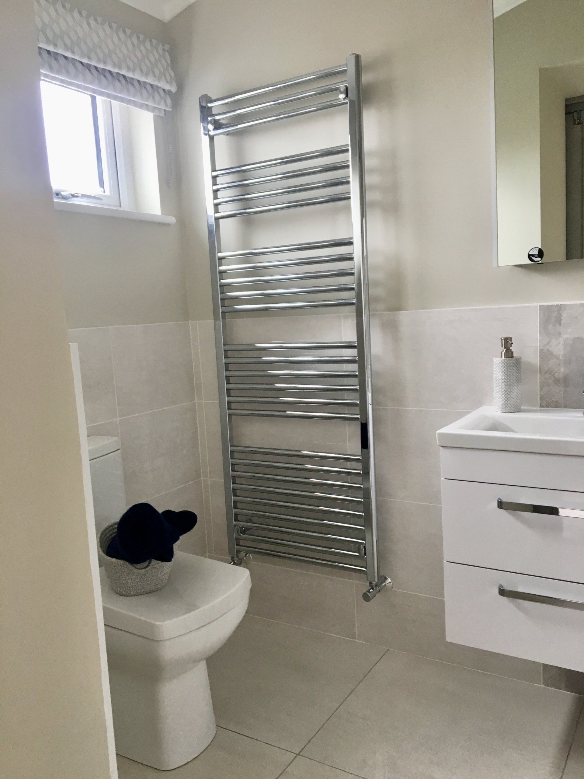 A bathroom with a toilet , sink and towel rack.