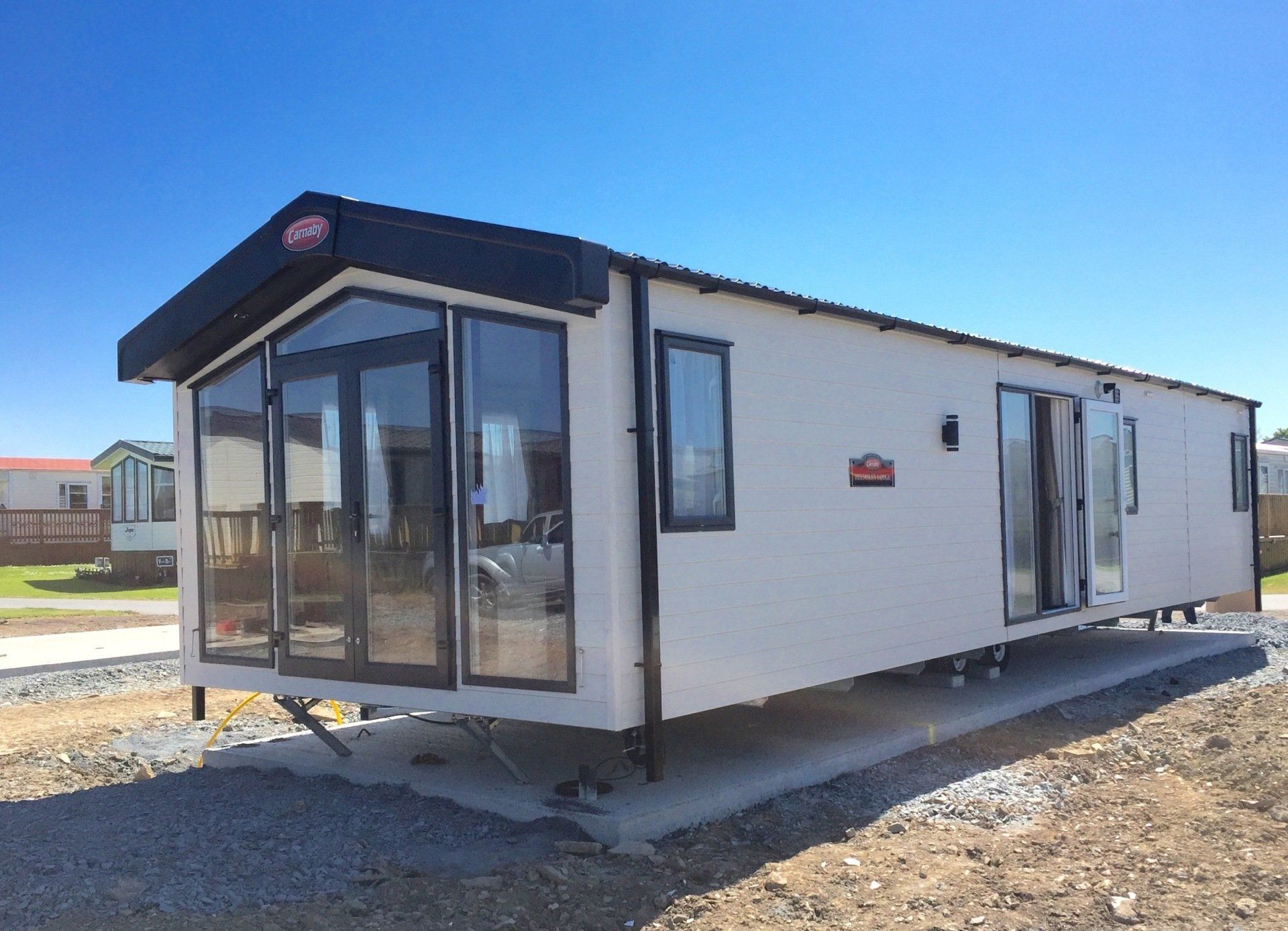 A mobile home with a lot of windows is parked on the side of the road.