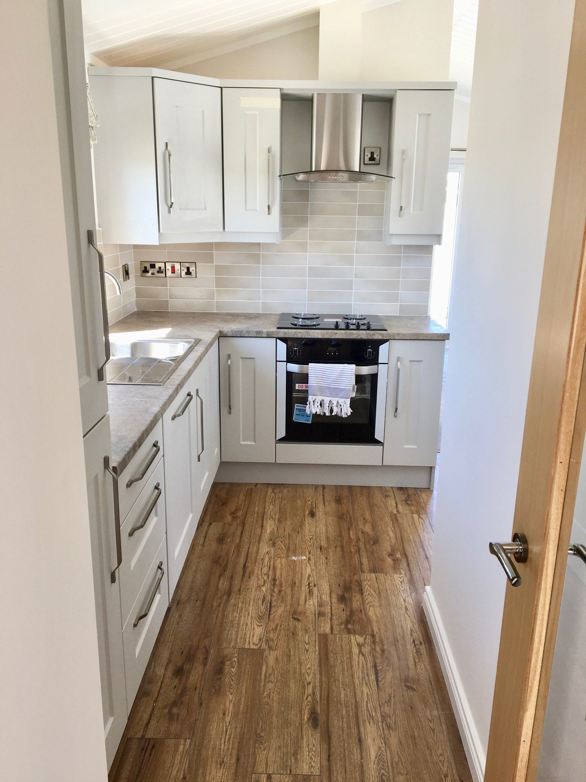 A kitchen with white cabinets and a wooden floor.