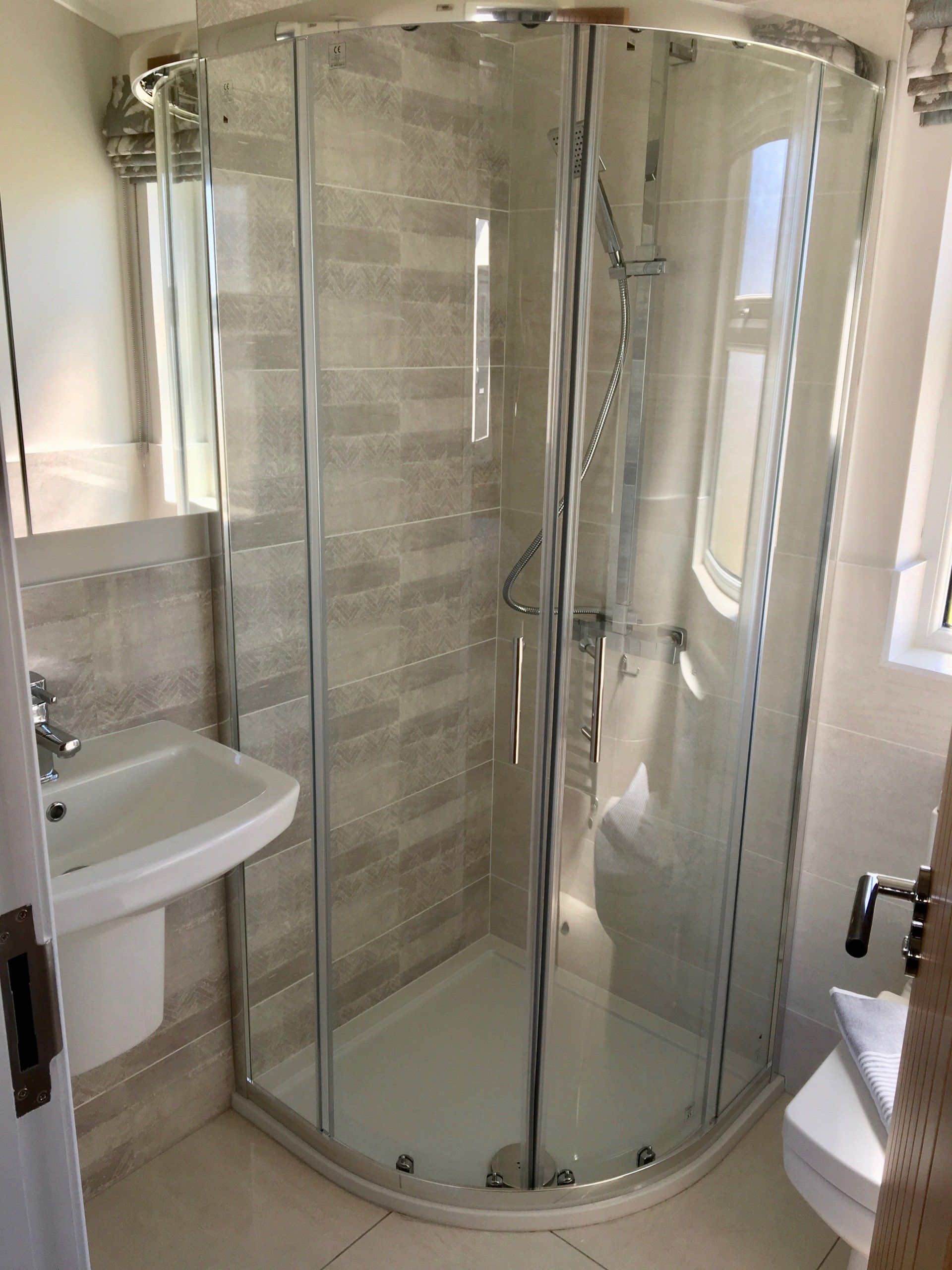 A bathroom with a shower , sink , toilet and mirror.