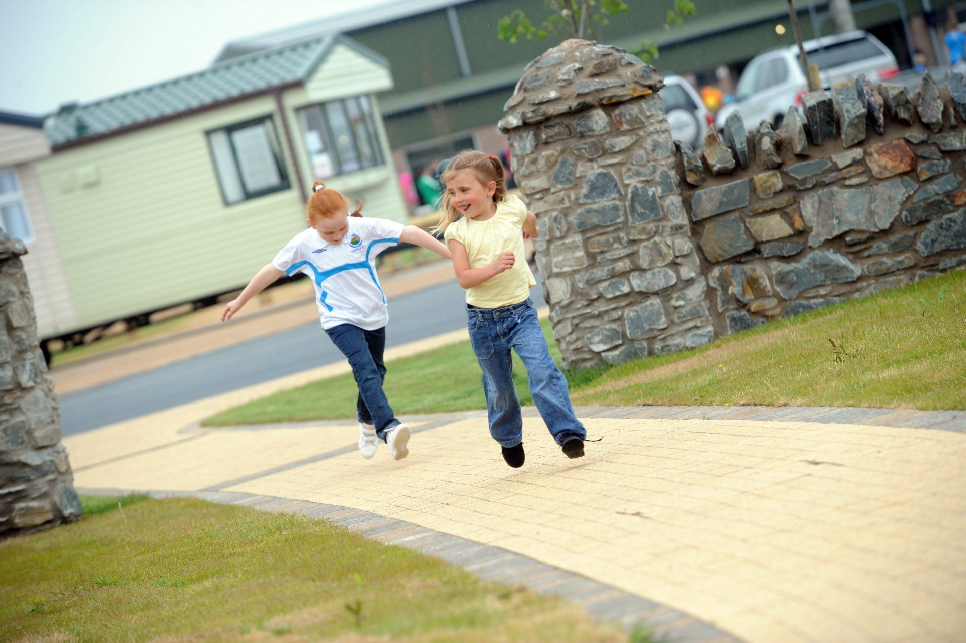 Two young girls are running down a path holding hands.