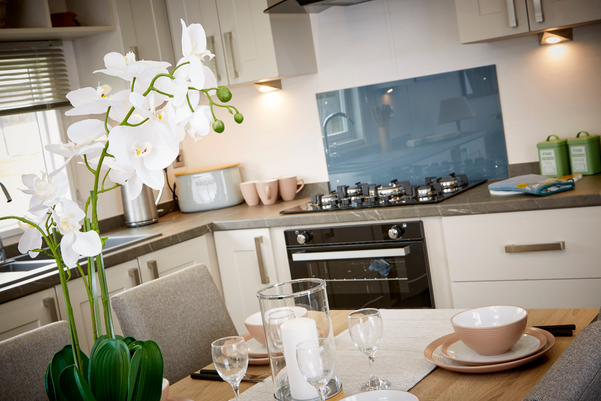 A kitchen with a table and chairs and a vase of flowers.