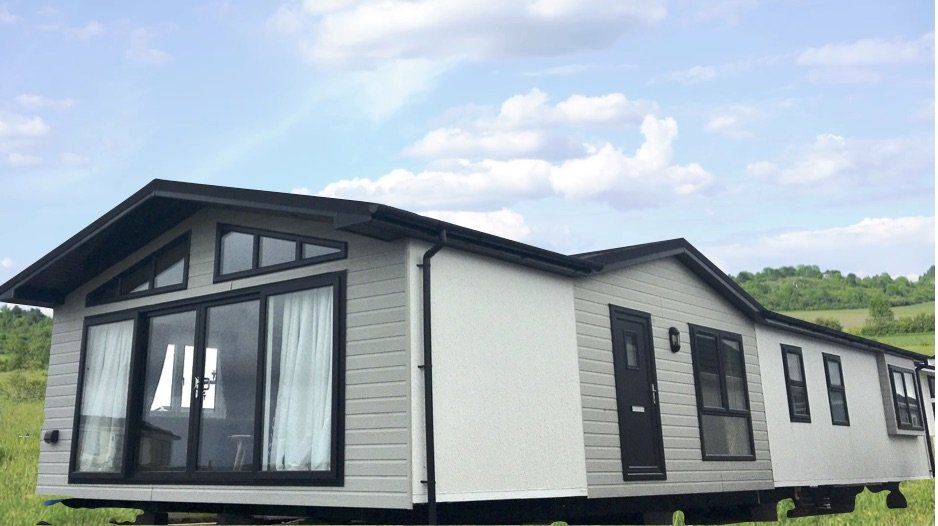 A mobile home is sitting in the middle of a grassy field.