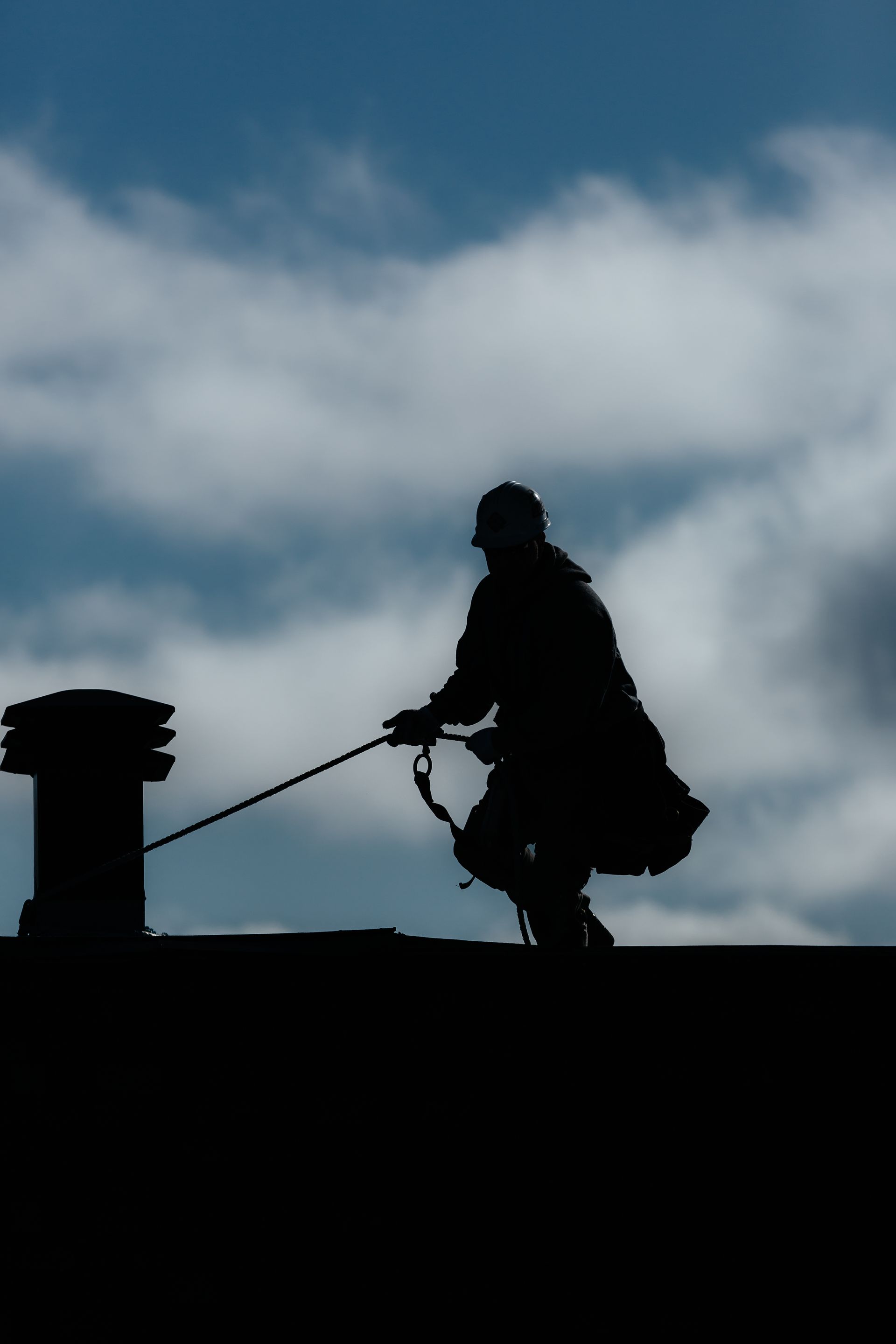 Une silhouette d'un homme nettoyant une cheminée sur un toit