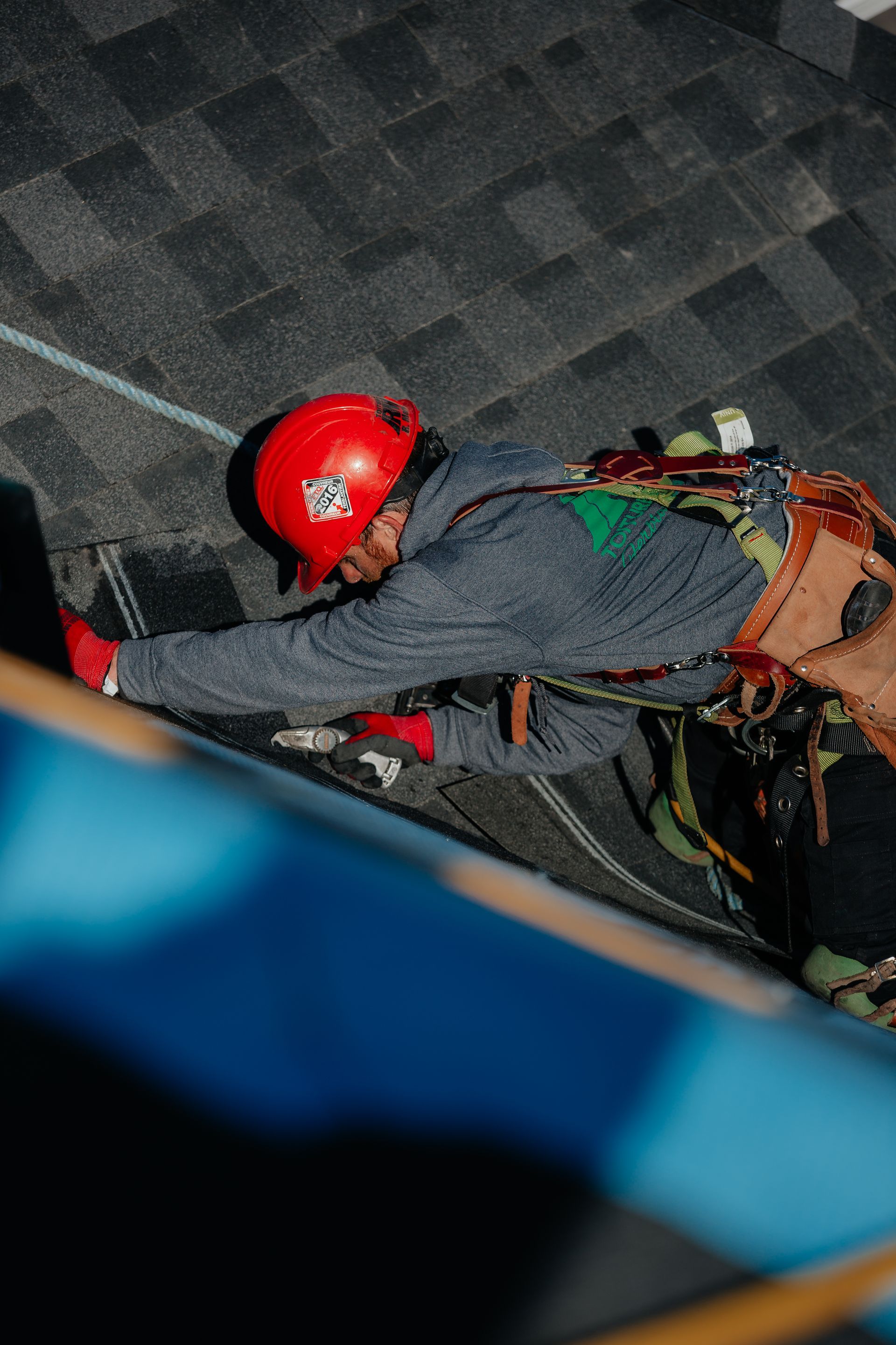 Un homme portant un casque rouge travaille sur un toit.