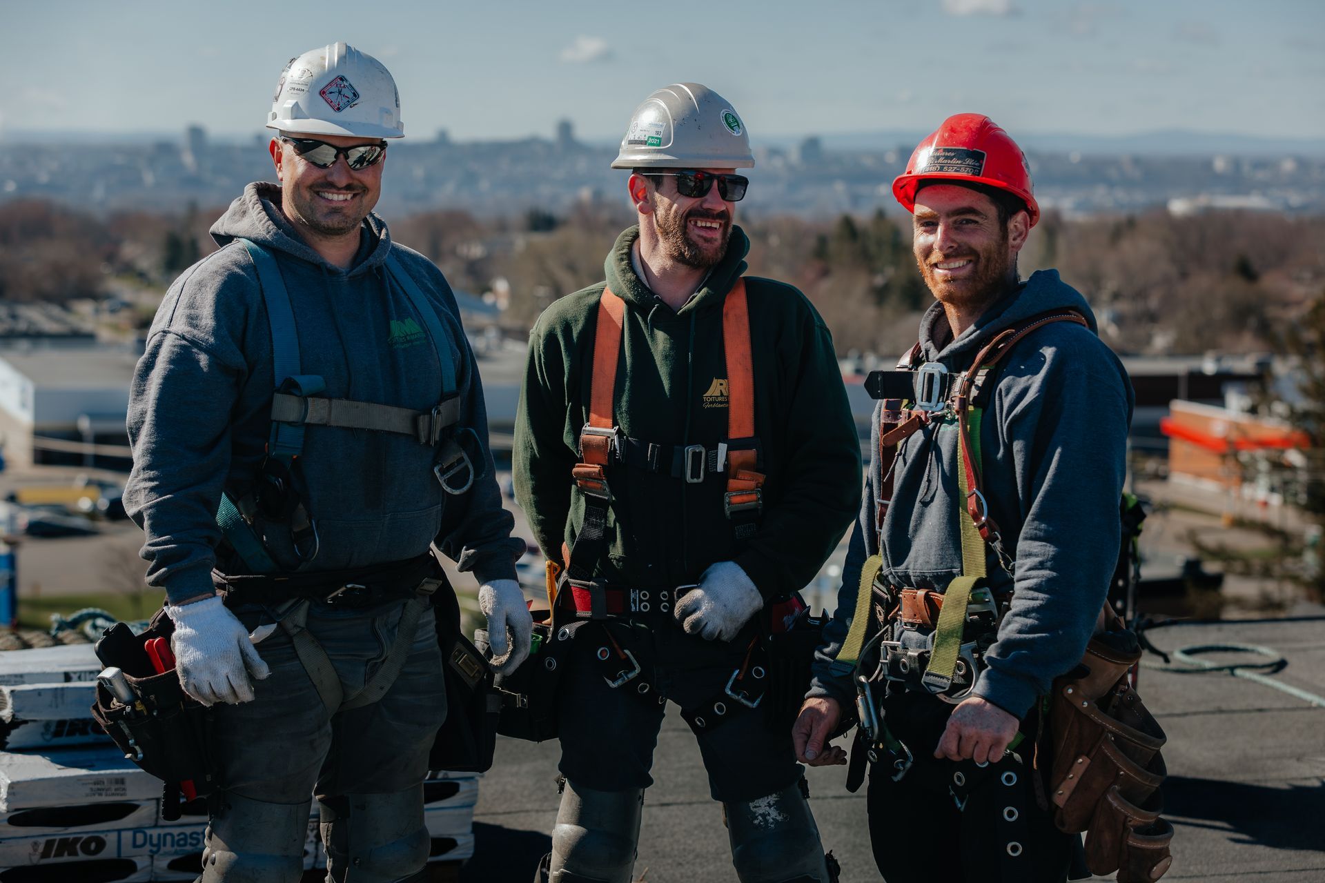 Trois ouvriers du bâtiment se tiennent côte à côte sur un toit.
