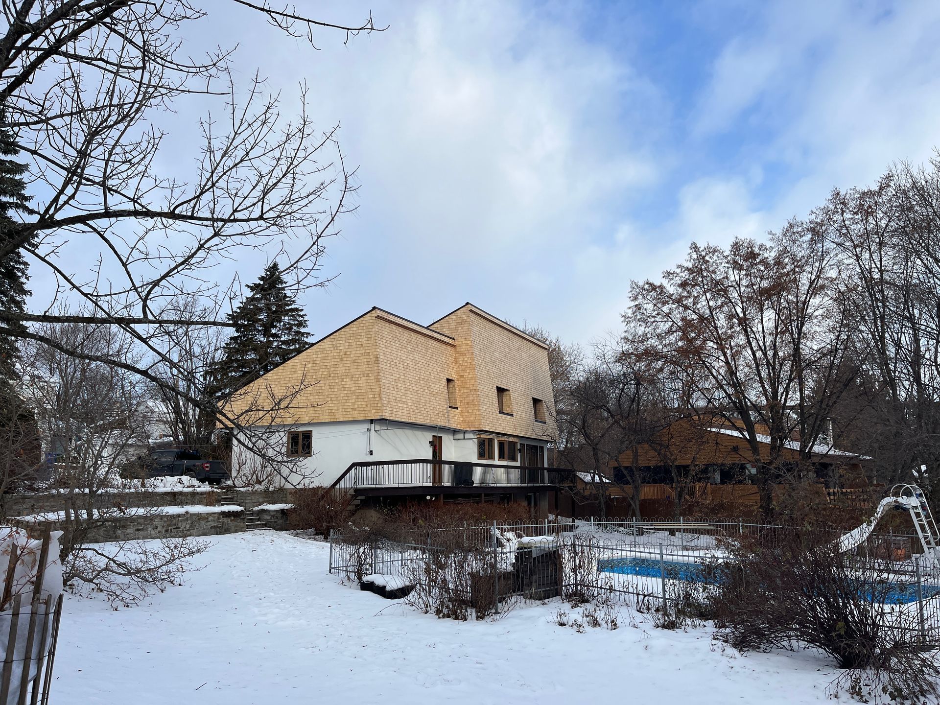 Une maison avec un toit en bois est entourée de neige et d'arbres.