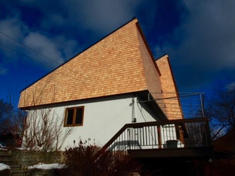 Une maison blanche avec un toit en bois et un balcon