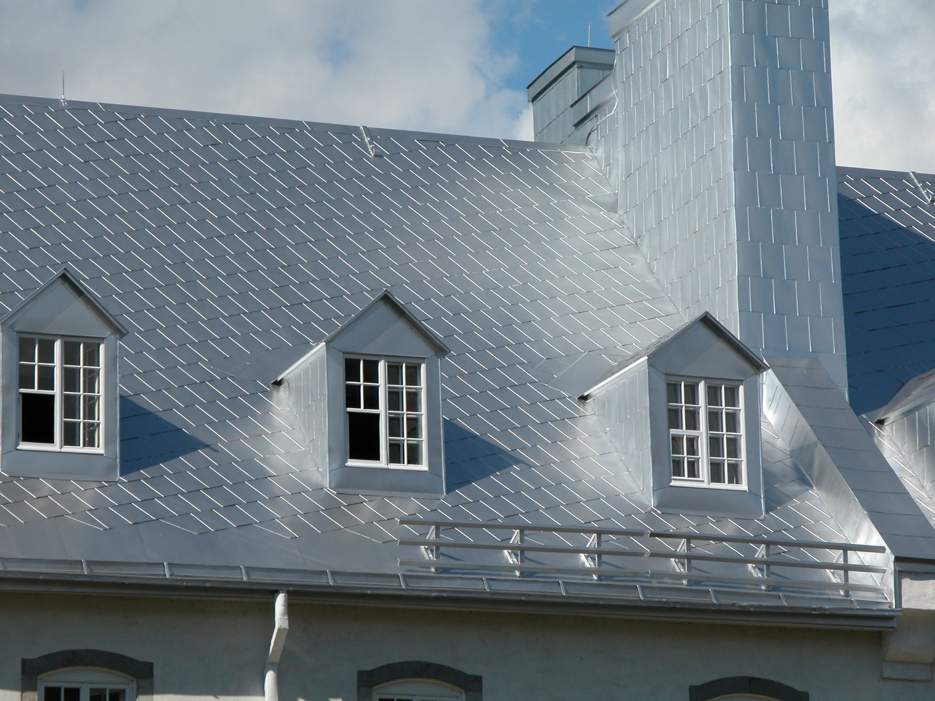 Un bâtiment blanc avec un toit et des fenêtres argentés