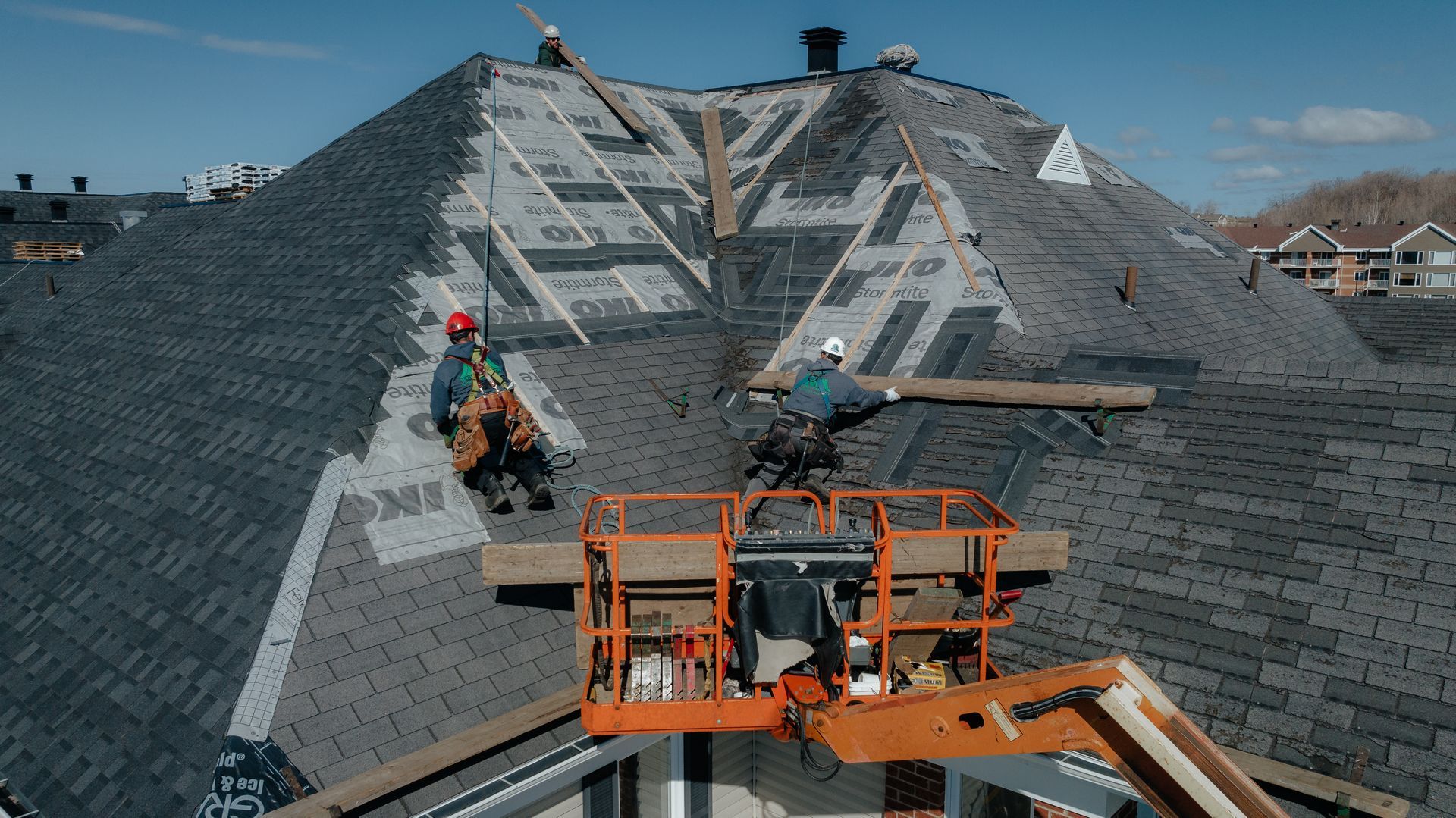 Un groupe d'hommes travaillent sur le toit d'une maison.