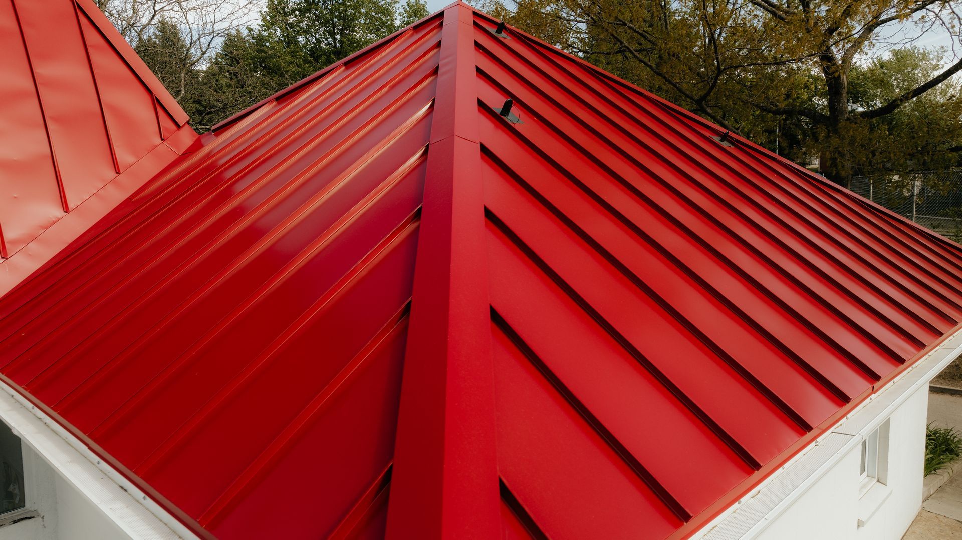 Un toit rouge sur une maison blanche avec des arbres en arrière-plan