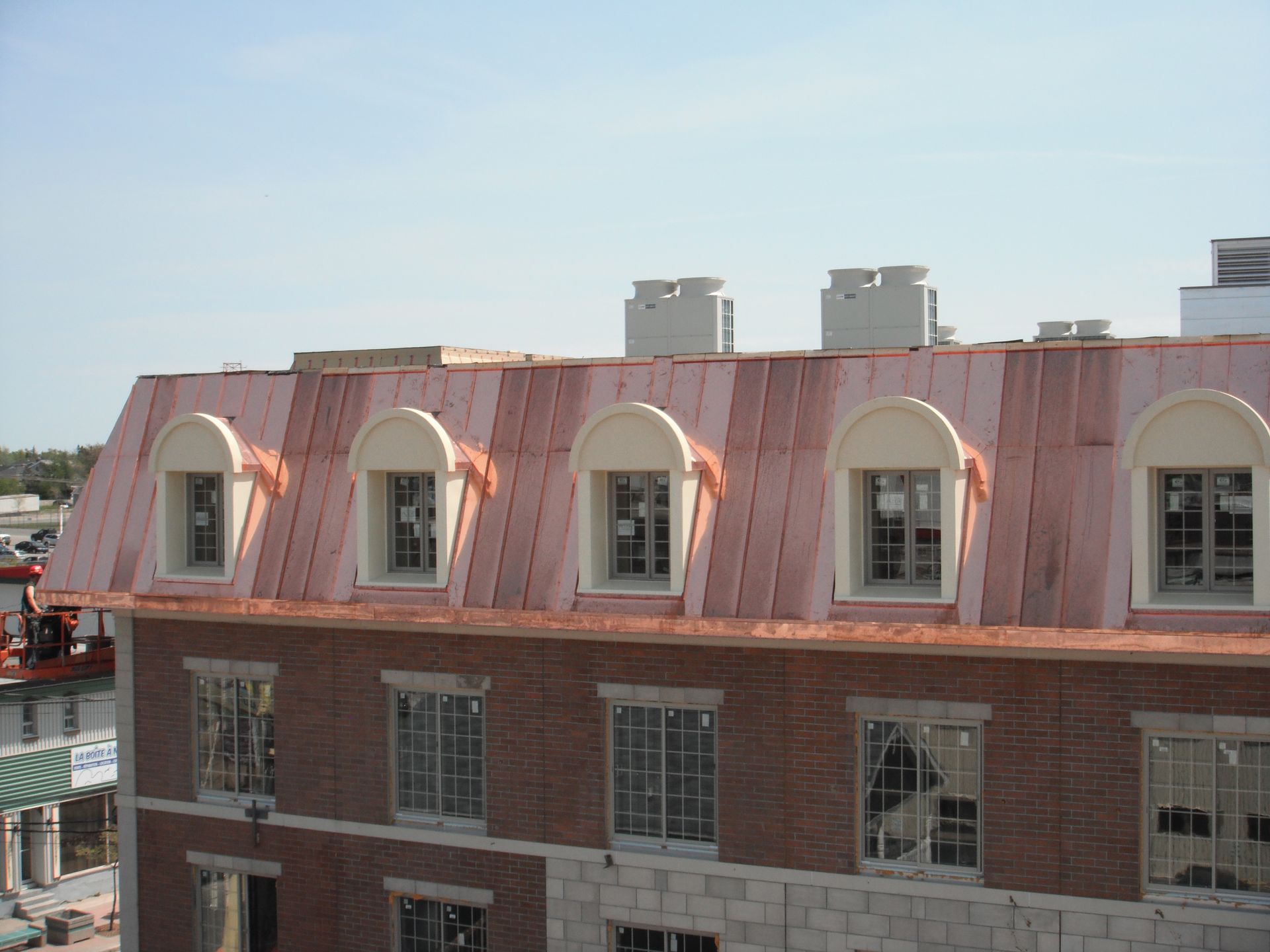 Un bâtiment en brique avec un toit en cuivre et des fenêtres cintrées