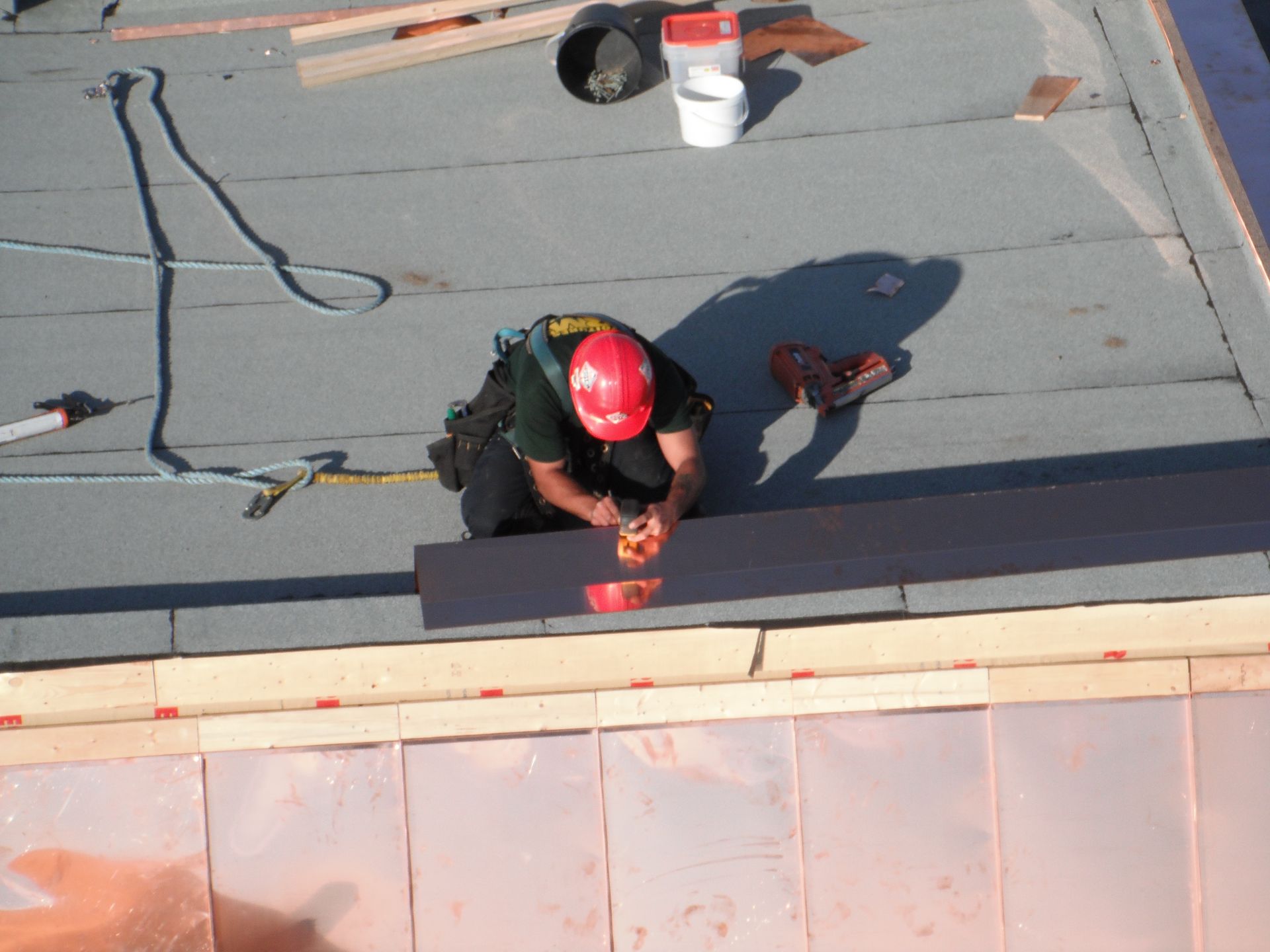 Un homme portant un casque rouge travaille sur un toit