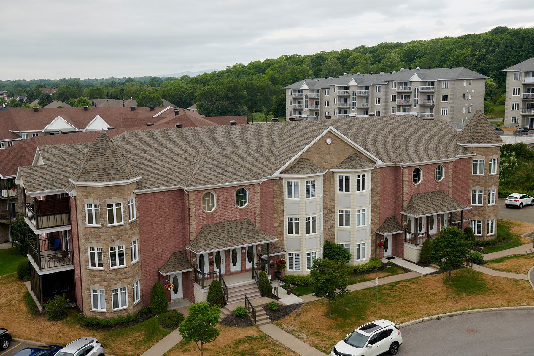 Immeubles d'appartements en briques de plusieurs étages avec des touches de gris clair et des balcons ; ciel couvert.