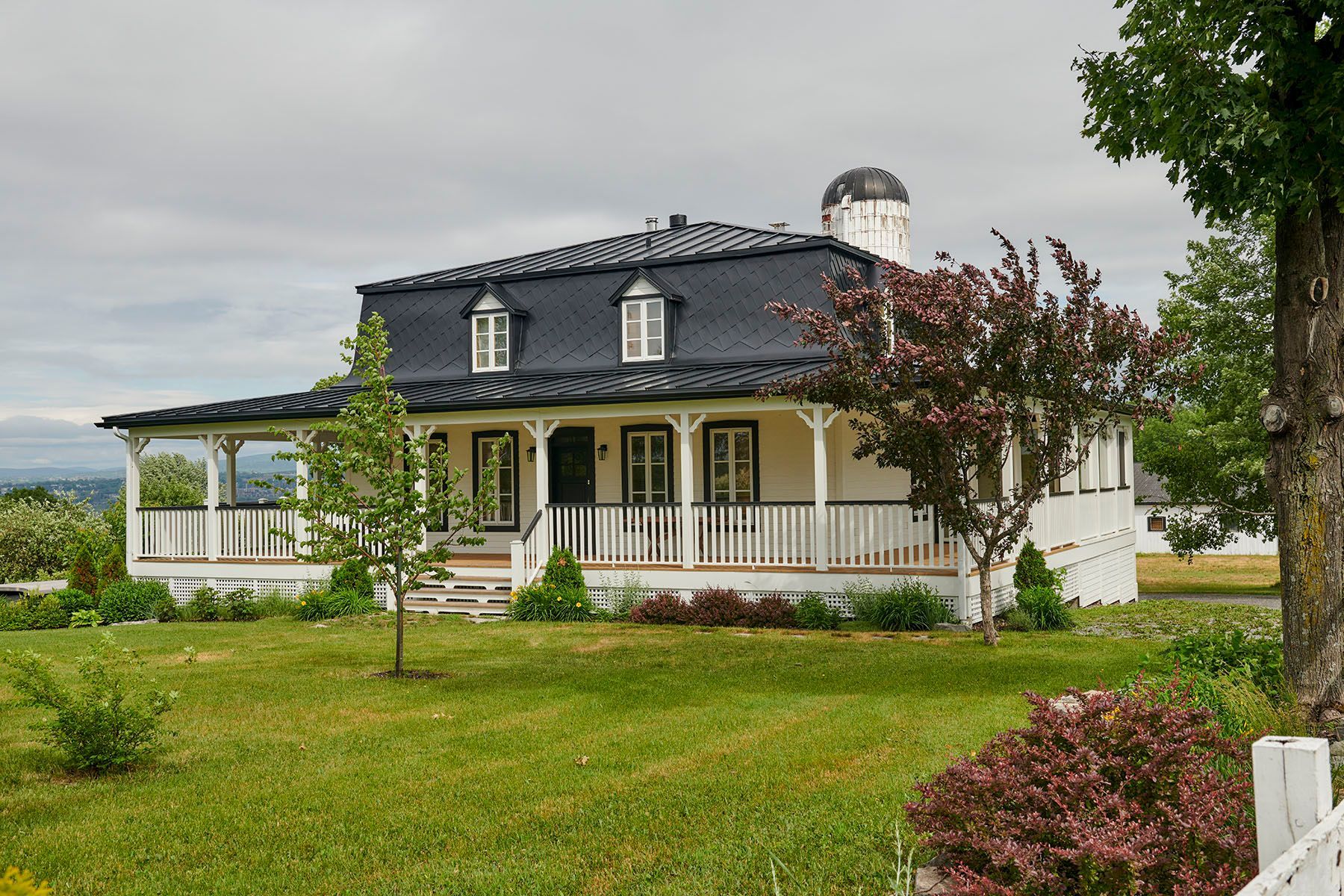 Une grande maison blanche avec un toit noir et un porche