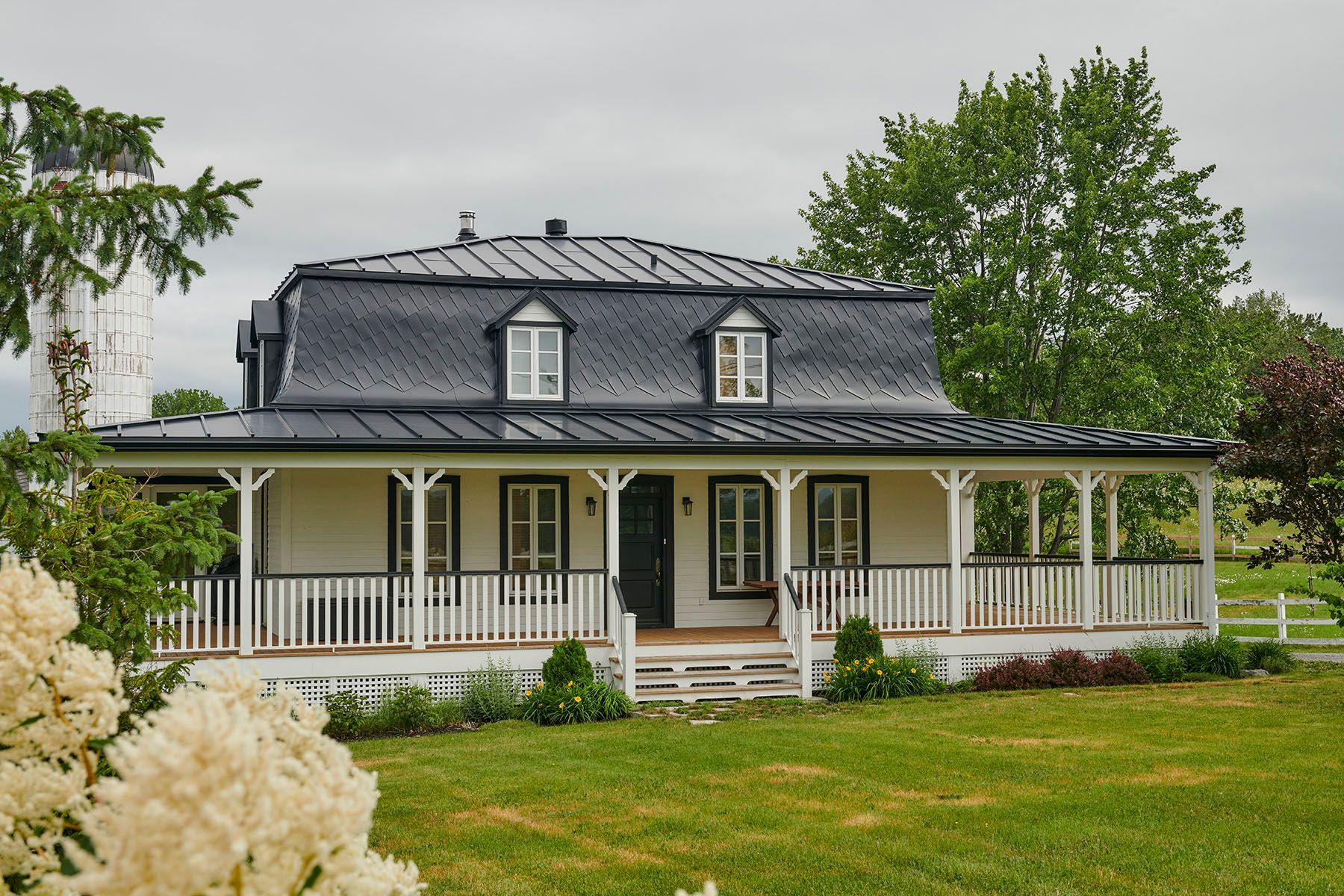 Une maison blanche avec un porche et un toit noir