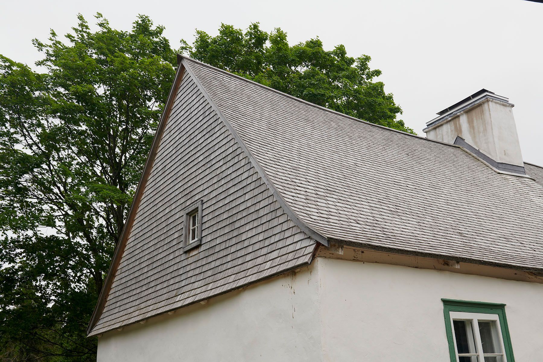 Une maison blanche avec un toit gris et une fenêtre