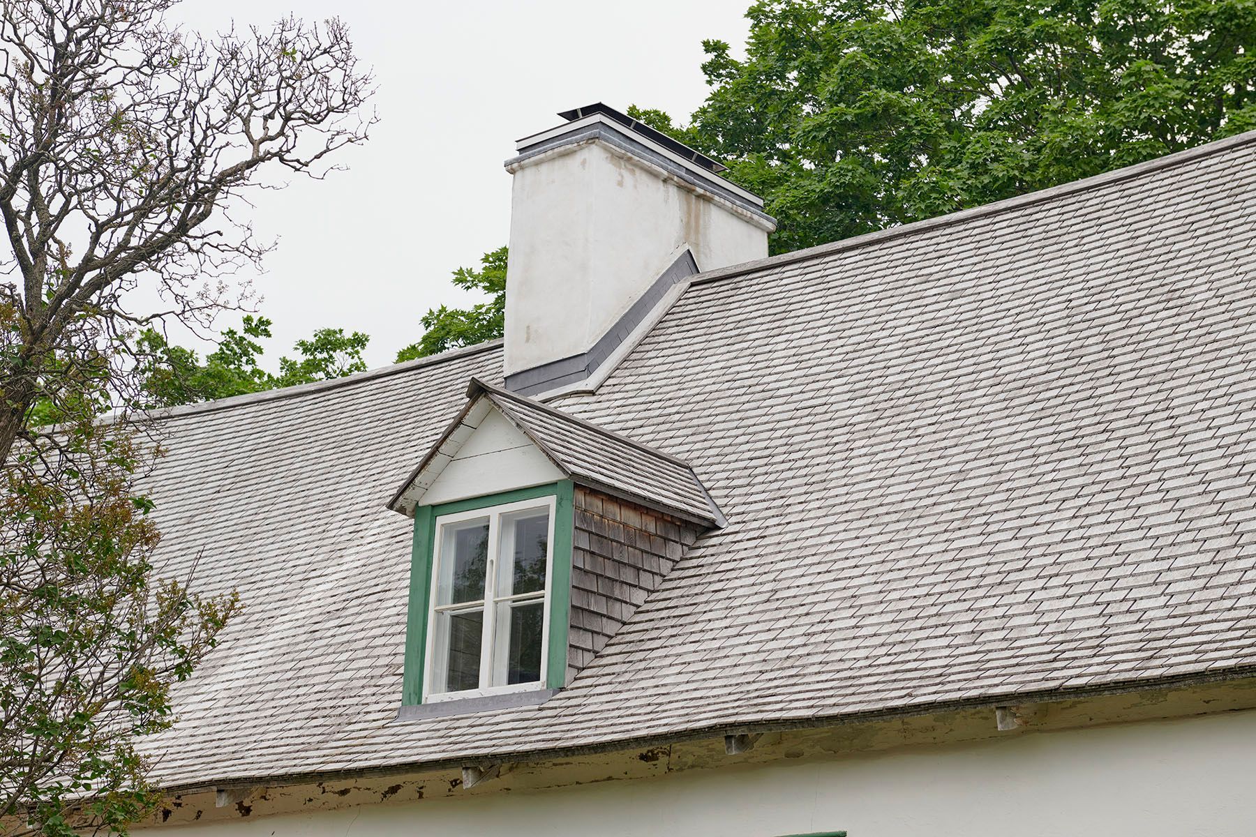 Une maison blanche avec un toit gris et une fenêtre verte