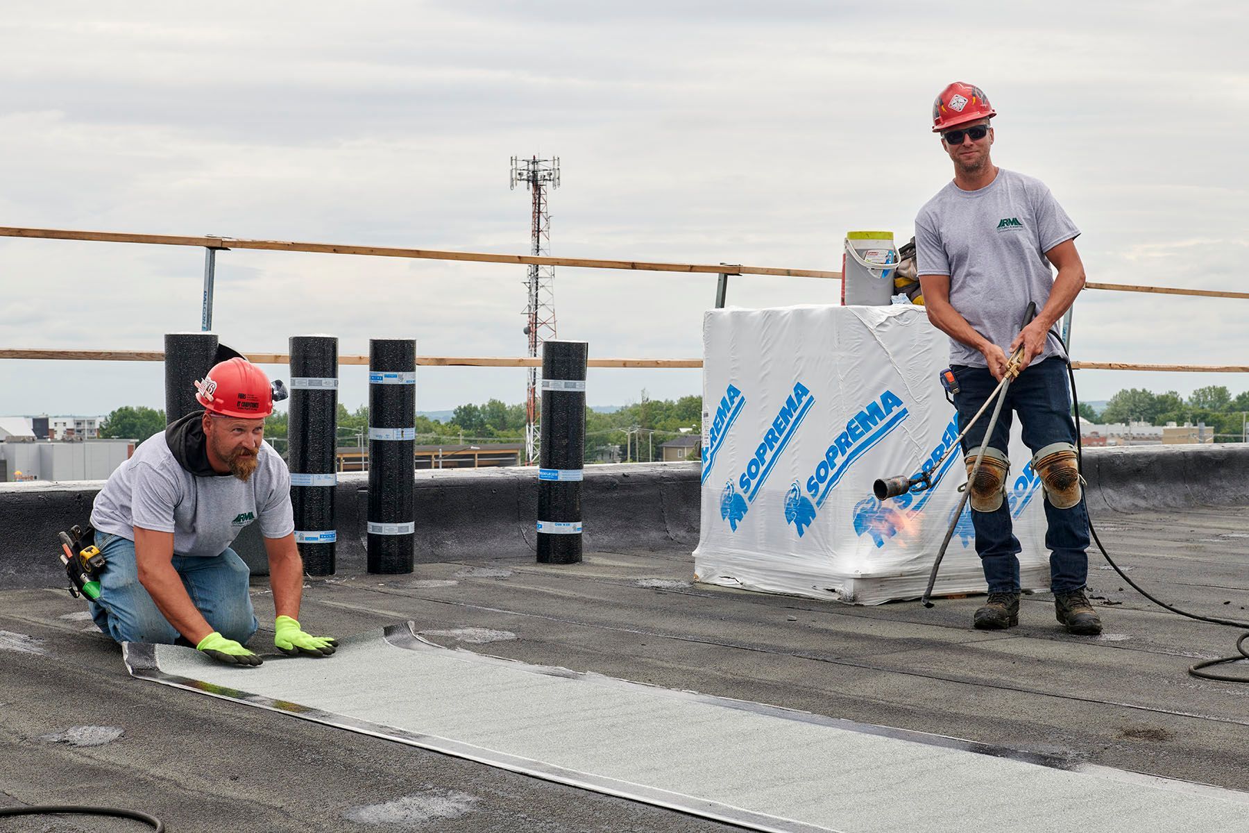 Deux hommes travaillent sur un toit et l'un d'eux porte un casque de sécurité.